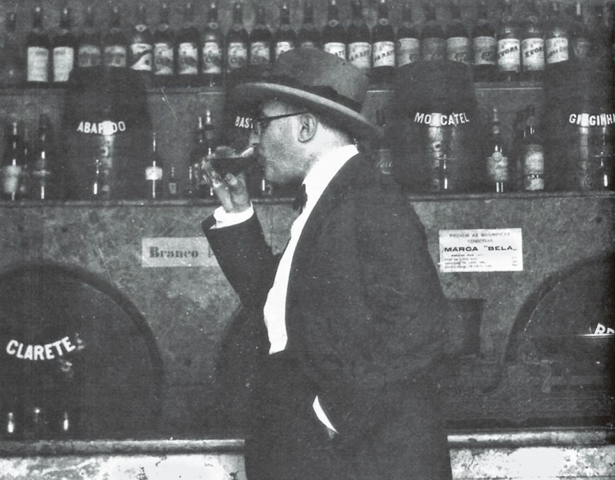 Em flagrante: Fernando Pessoa bebendo vinho na firma Pereira da Fonseca à frente e um barril de clarete