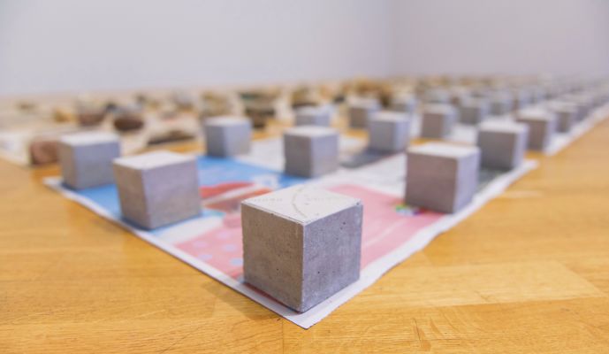 Na obra 'Primeira pedra', o artista propõe que o visitante saia da exposição em busca de uma pedra para trocar por um dos cubos de concreto utilizados por ele. Imagem: Levi Fanan/Divulgação